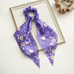 Detail of periwinkle blue silk hair scrunchie with floral pattern and long ribbons