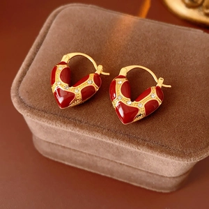 Detailed close-up of vintage heart earrings with red enamel and crystals on velvet