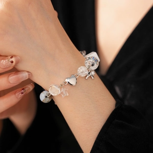 Macro shot of silver bow and star charms on a beaded bracelet with transparent pearls