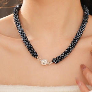 Close-up of multi-strand twisted black faceted glass beads with a pave crystal sphere clasp