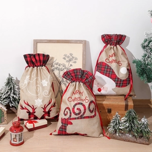 Three assorted sizes of burlap Christmas drawstring gift bags with reindeer and Santa designs