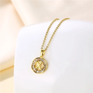 Macro view of 18K gold letter X pendant with sparkling cubic zirconia on beige silk