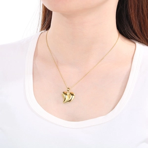 Detail showing a golden heart pendant necklace with sleek texture on a female model
