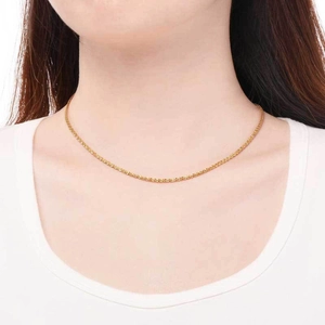 Gros plan d'un collier chaîne torsadée dorée porté par un mannequin sur fond blanc