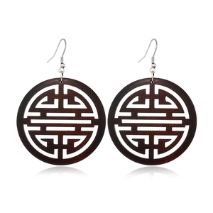 Macro detail of dark brown round hollow wooden earrings with traditional pattern
