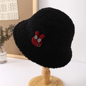 Close-up of plush black bucket hat featuring a cute red bunny patch and textured faux fur