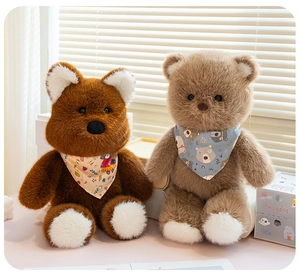 Close-up of two plush teddy bears in brown and tan with patterned neck scarves on a desk