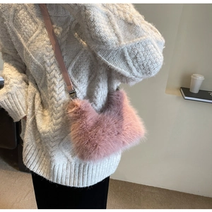 Detailed view of a soft pink faux fur crossbody bag paired with a white cozy knit sweater