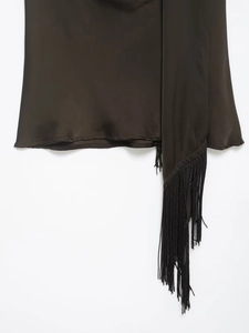 Close-up of glossy satin fabric and elegant long fringe detail on the garment hem