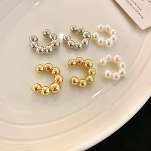 Dettaglio macro di eleganti ear cuff a forma di C con perle dorate e argento su porcellana