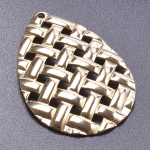 Macro shot of 18k gold-plated teardrop pendant with woven texture and top loop