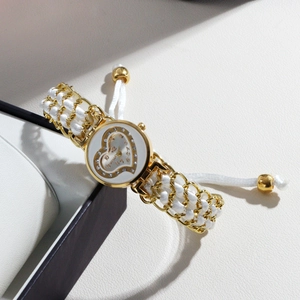 Detail of heart-shaped quartz watch with gold and white braided chain bracelet band