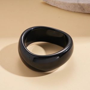 Close-up of black acrylic bangle featuring a glossy finish and organic wavy structure