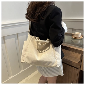 Detail of beige corduroy tote bag showing material texture and long shoulder strap