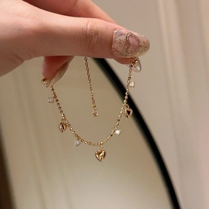 Sparkling gold heart charm bracelet with zircon stones held in hand for a sweet look