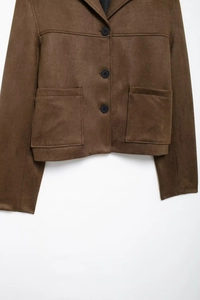 Close-up of brown suede jacket detailing texture, black buttons, and large front pockets