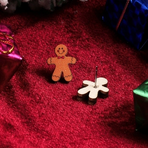Detail of gingerbread man stud earring on red velvet with festive Christmas decorations