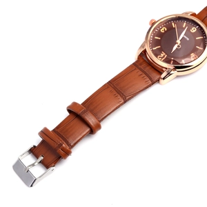 Macro shot of brown leather watch strap with gold buckle and minimalist quartz dial