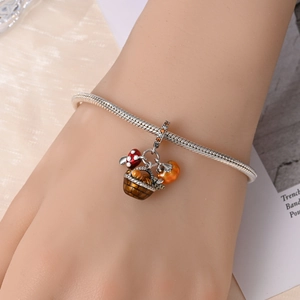 Detailed close-up of a silver charm bracelet with autumn basket mushroom and pumpkin charms