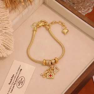 Detailed shot of gold plated medical theme bracelet with stethoscope and cross pendants