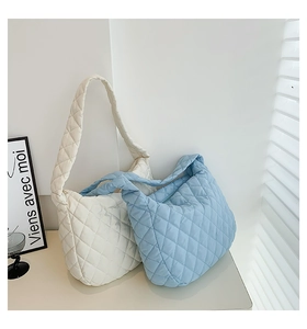 Quilted cloud tote bags in off-white and light blue displayed against a clean wall