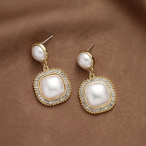 Detailansicht der Vintage-Ohrhänger mit Perlen und Strass auf brauner Seide