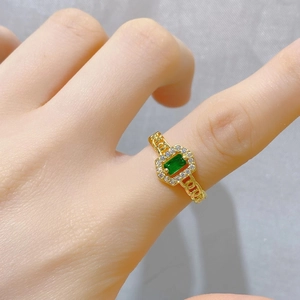 Makroansicht Goldring mit grünem Stein im Smaragdschliff und Gliederkette