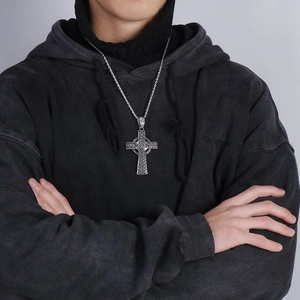 Close-up of a silver Celtic cross necklace with intricate knot patterns on a male model