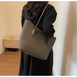 Detail of dark grey woven tote bag on shoulder showing large capacity and texture