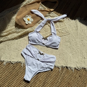 Dettaglio flat lay di un bikini bianco con anelli a cuore dorati e accessori estivi