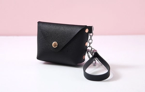 Detail of black PU leather mini coin purse showing fine texture and metal keychain clasp