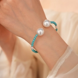 Détail d'un bracelet en perles avec de grandes perles blanches et des billes turquoise