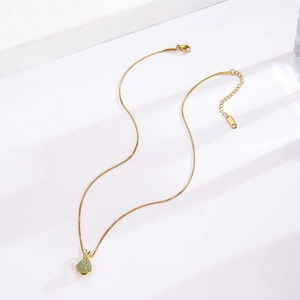 Detail of gold titanium necklace with faux jade pendant and sparkling bow decoration