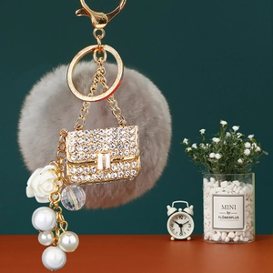 Detail of luxury grey pompom keychain with crystal mini bag and pearl flower charms