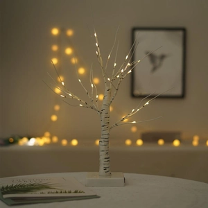 Close-up of warm white LED lights on a white birch tree lamp for indoor home decoration