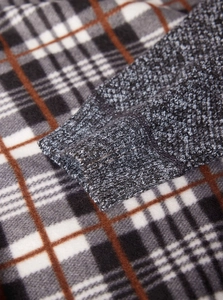 Dettaglio macro del tessuto scozzese foderato in pile e polsini in maglia del cardigan