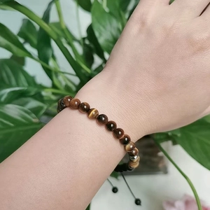 Detailed close-up of tiger eye bead bracelet with morse code design on a female wrist
