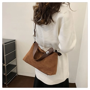 Détail du sac bandoulière en daim marron avec sangle en cuir et fermoir en métal argenté