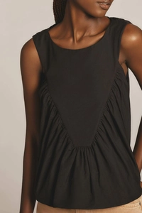 Detail of black sleeveless top featuring elegant V-shaped pleats and gathered fabric texture