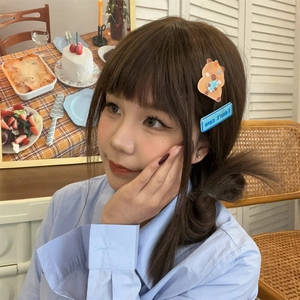 Detail of cute Capybara bear and blue letter acrylic hair clips worn on side hair