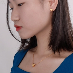 Set collana e orecchini a cuore placcati in oro 14k indossati da una modella per un look dolce