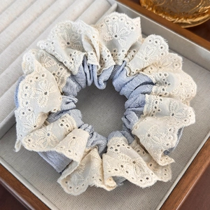 Detail of blue plaid fabric hair scrunchie with cream lace trim on a jewelry tray
