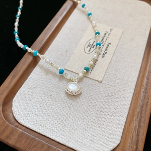 Dettaglio della collana con turchese blu perle e ciondolo tondo in conchiglia