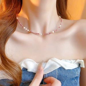 Close-up of pink beaded necklace with white pearls and gold spacers on a model's neck