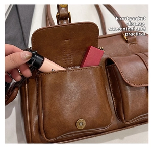 Detail of brown leather shoulder bag featuring functional front pockets and magnetic snap