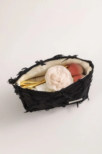Close-up of black tweed fabric texture and spacious interior of the tassel makeup bag