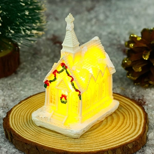 Close-up of a white resin Christmas church miniature with LED lights and snow texture