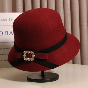 Détail macro du chapeau cloche en laine bordeaux avec ruban noir et boucle en strass