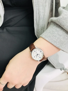 Close-up of small quartz watch with leather strap and day-date window on female wrist