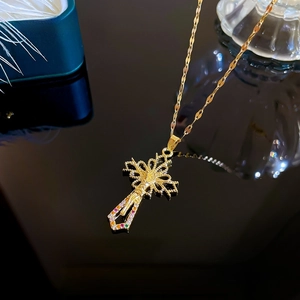 Macro detail of gold cross pendant with colorful zircon stones and Jesus relief